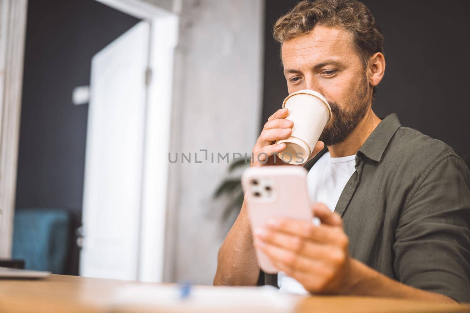 Copywriter focusing on their phone while enjoying cup of coffee home. Concept of working from home is emphasized here, highlighting freedom and flexibility that comes with being self-employed freelancer. High quality photo
