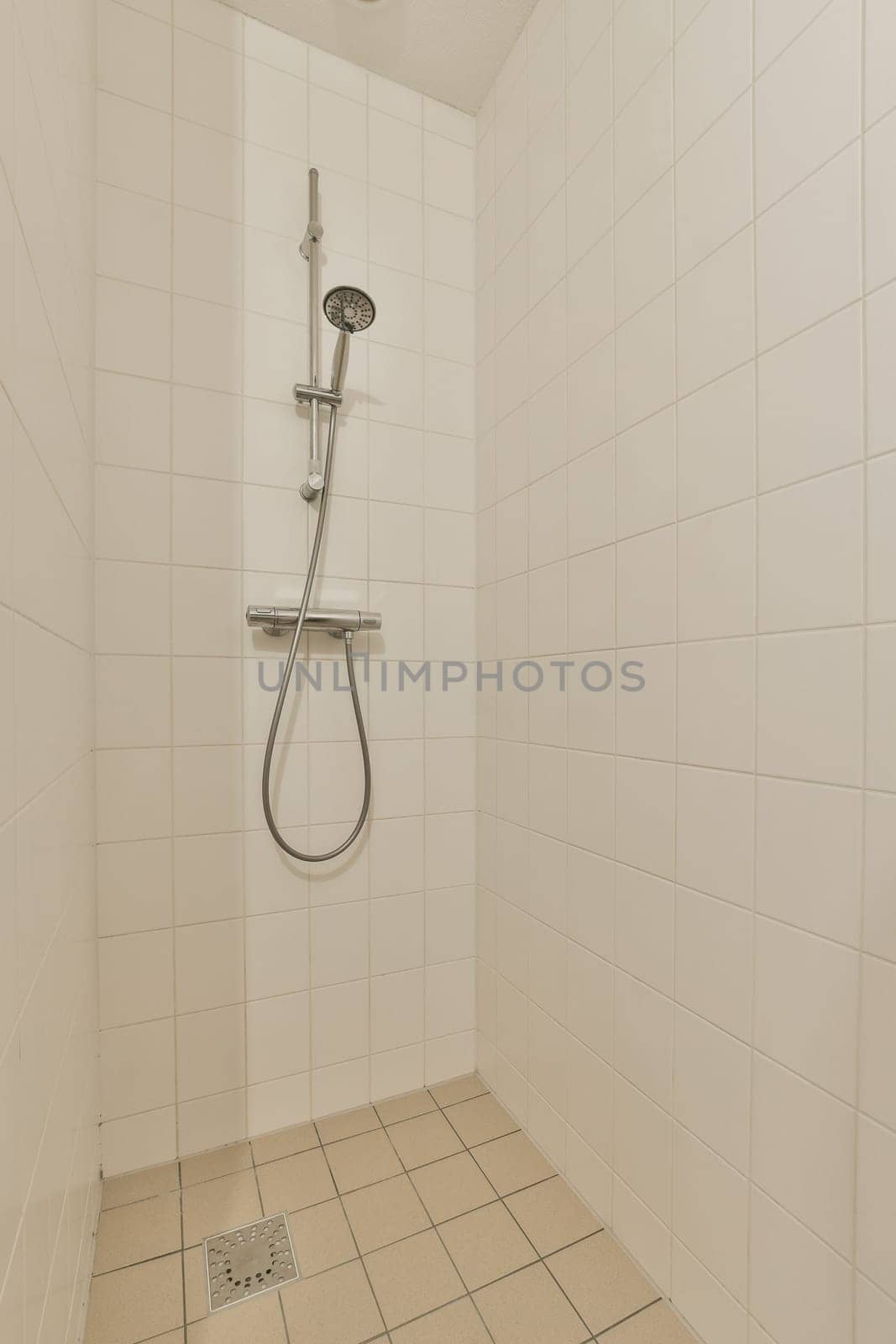 a white tiled bathroom with a shower head and hand rail in the wall is made out of ceramic tiles on the floor