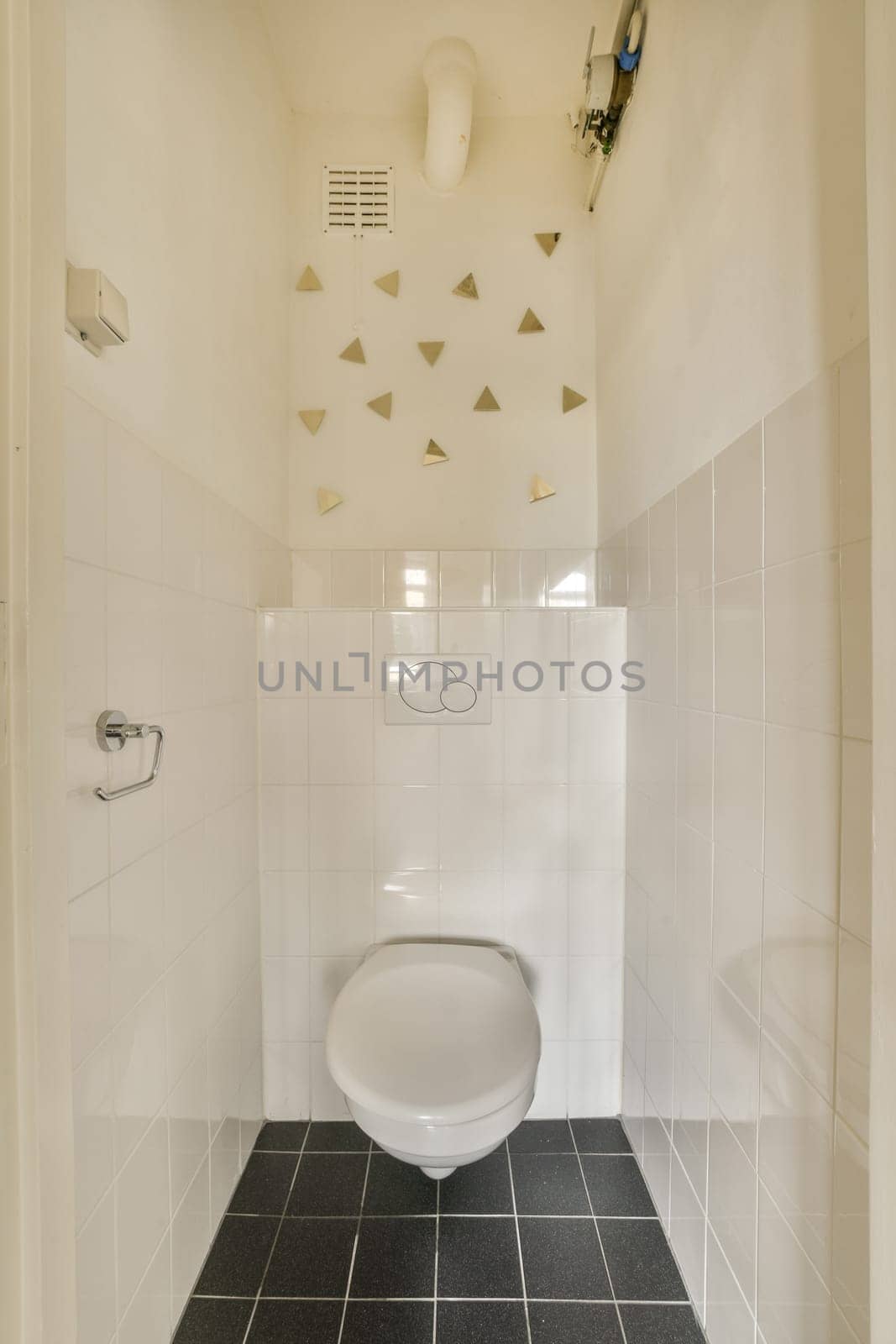 a white toilet in a bathroom with black and white tiles on the floor, walls, and ceiling above it