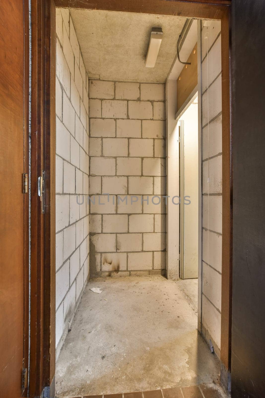 a corridor with white brick walls and a wooden door by casamedia