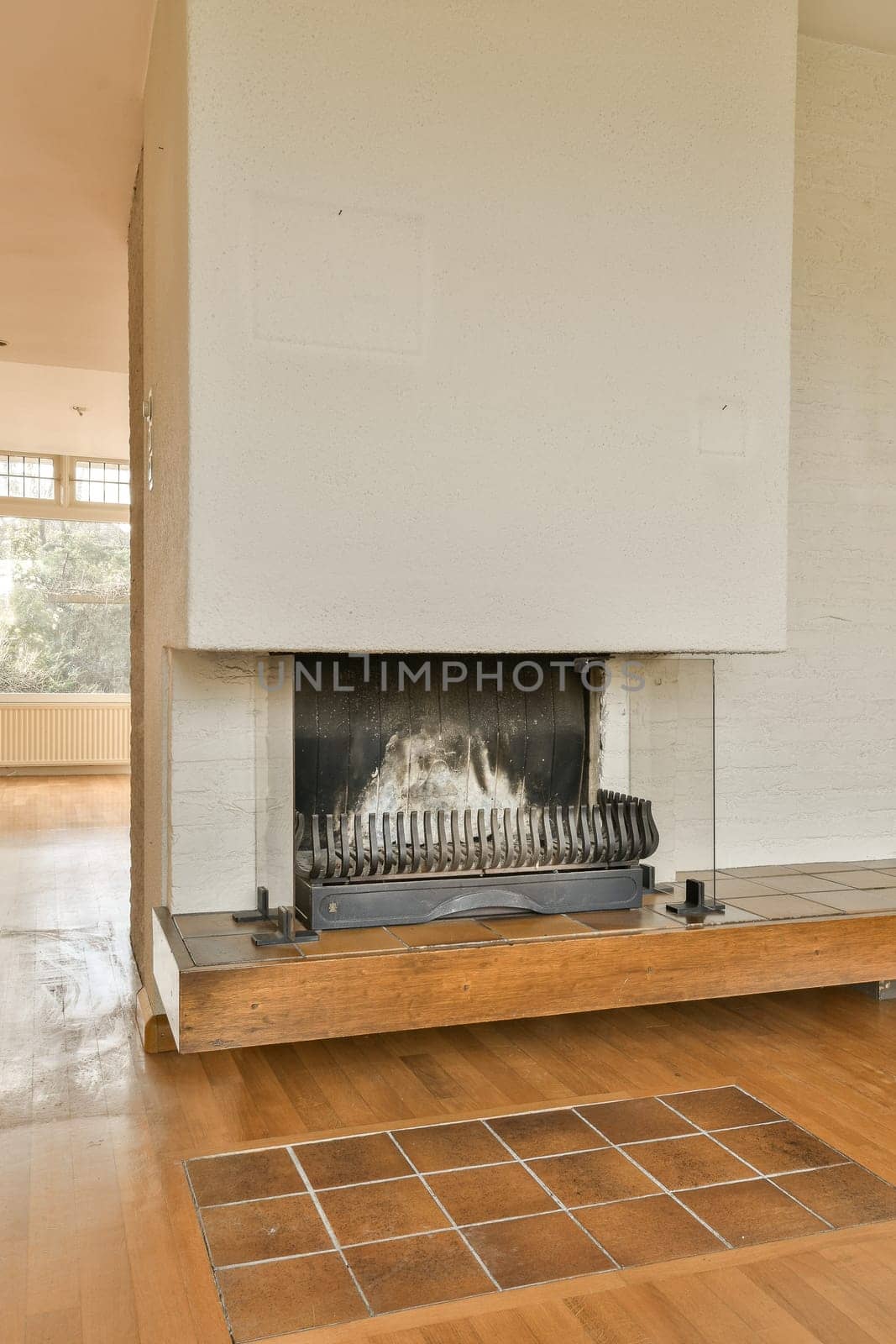 an empty living room with wood floors and a fire place in the fireplace is white brick on the wall behind