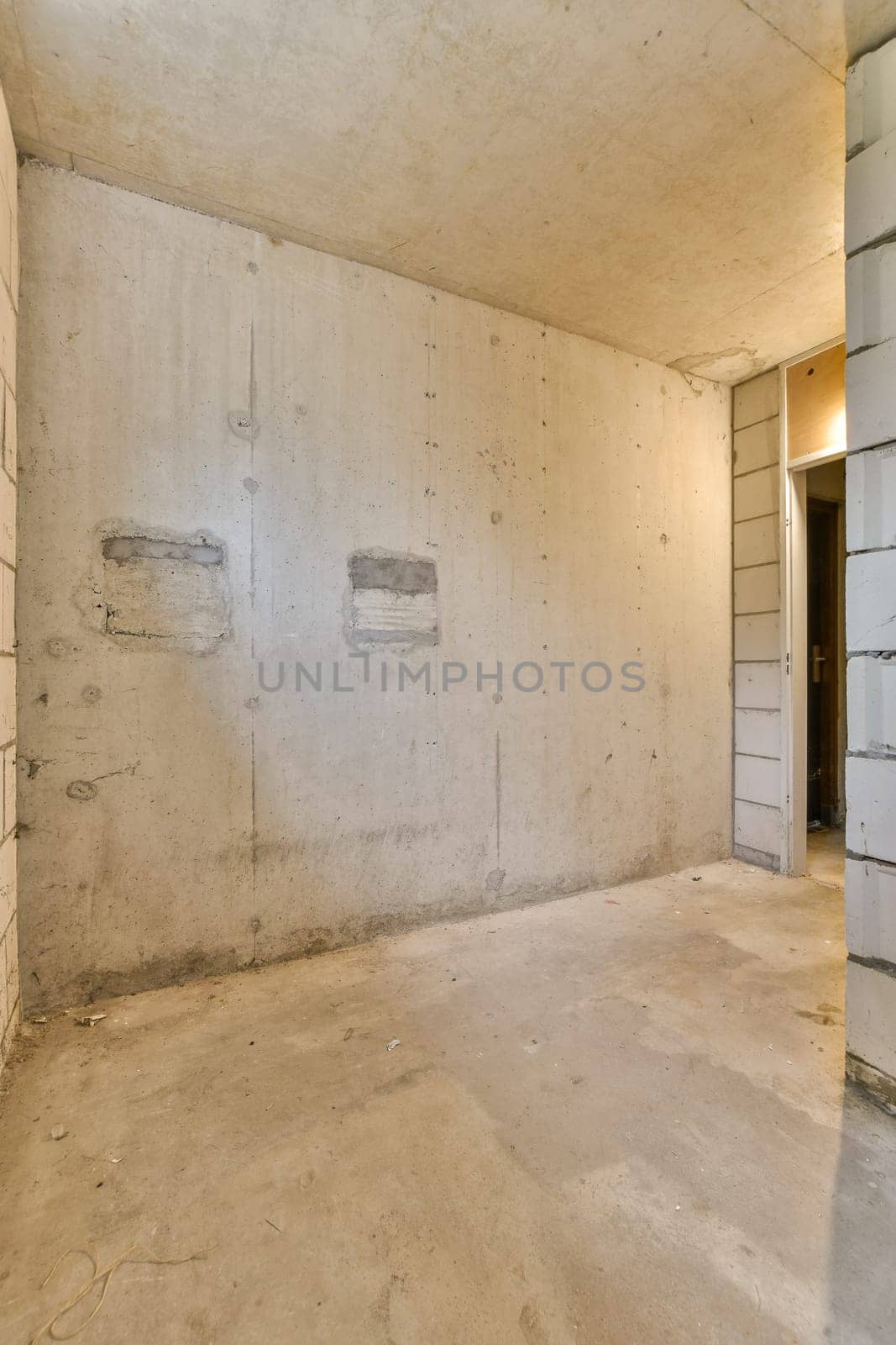 an empty room with a door and a concrete wall by casamedia