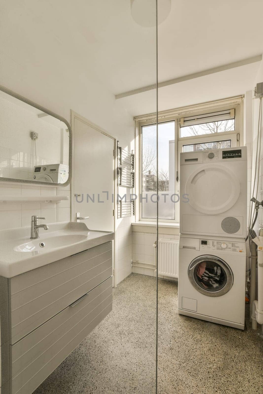 a laundry room with a washer and dryer in the corner, next to a window that looks out onto the street