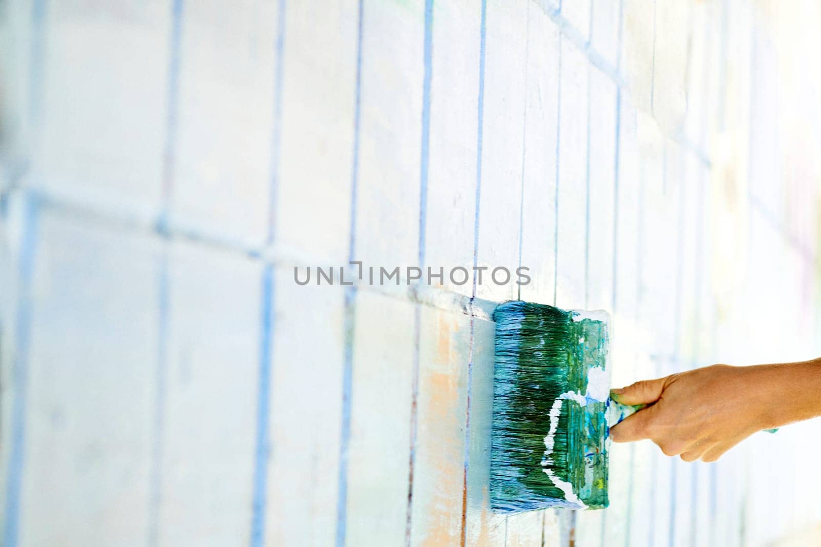 an implement with a handle, consisting of bristles, hair, or wire set into a block, used for cleaning, applying a liquid to a surface. Roller painting white wall surface with green emerald paint