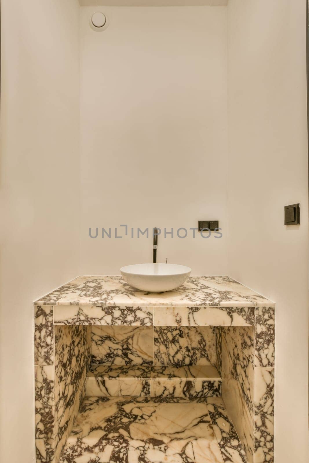 a marble sink in a white bathroom with black trim around the edge and an oval mirror on the wall above it