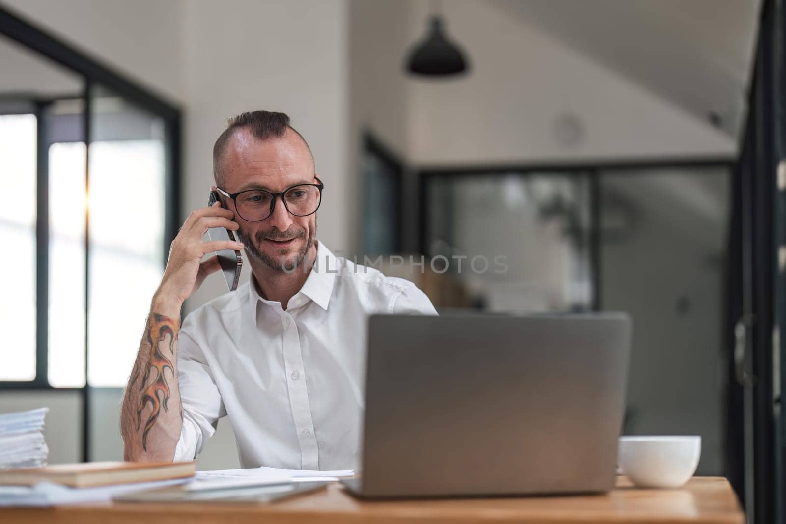 businessman talking on cell phone while working on computer in office.
