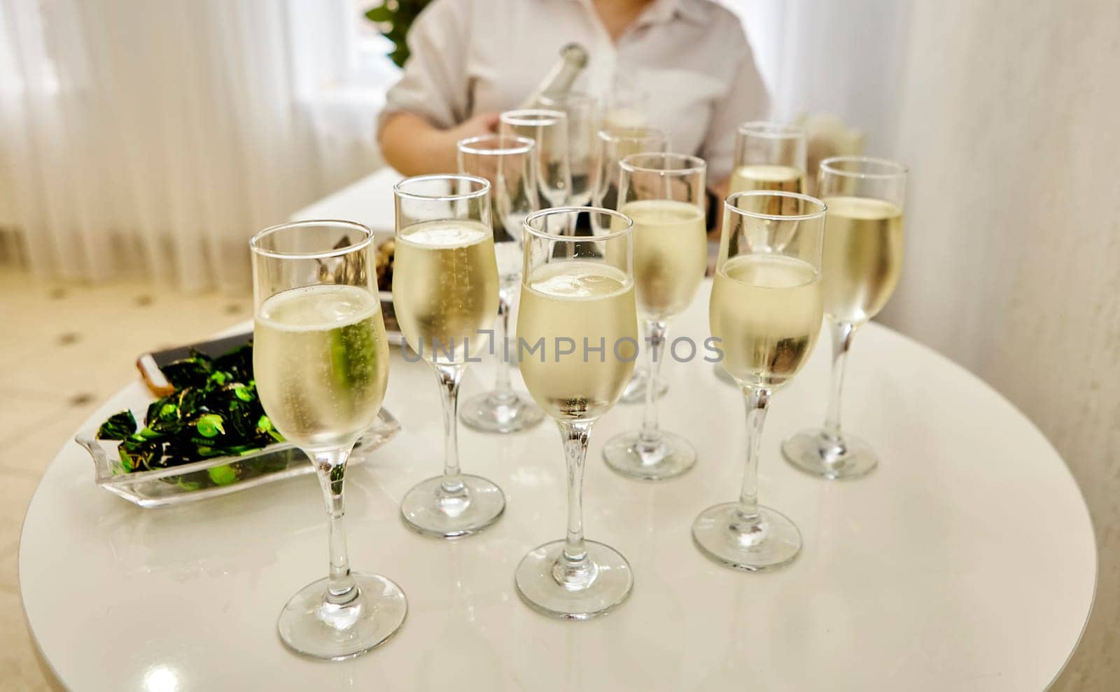 The waitress distributes sparkling white wine to the guests. A group of champagne glasses at a party.