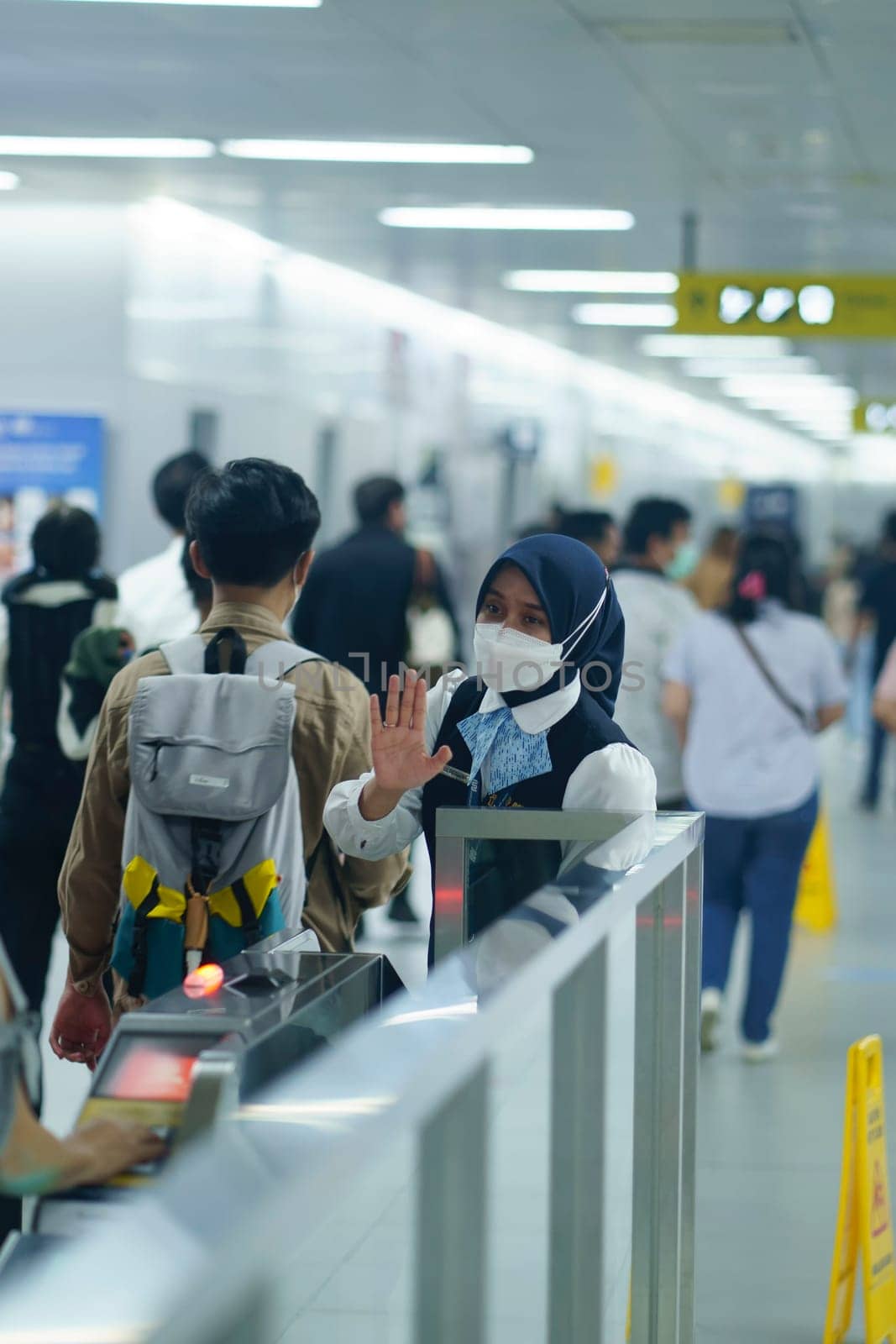 Friendly female officer greeting the passengers at the entry gate at MRT Station, Jakarta. Indonesia. April 20, 2023. Public service photography.