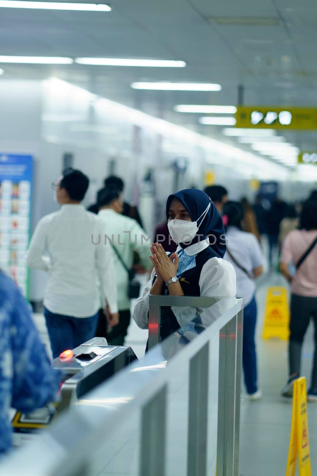 Friendly female officer greeting the passengers at the entry gate at MRT Station, Jakarta. Indonesia. April 20, 2023. Public service photography.