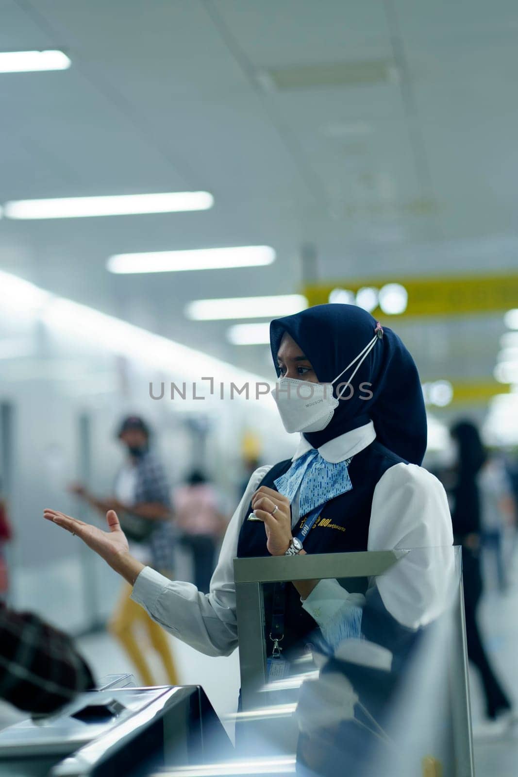 Friendly female officer greeting the passengers at the entry gate at MRT Station, Jakarta. Indonesia. April 20, 2023. Public service photography.