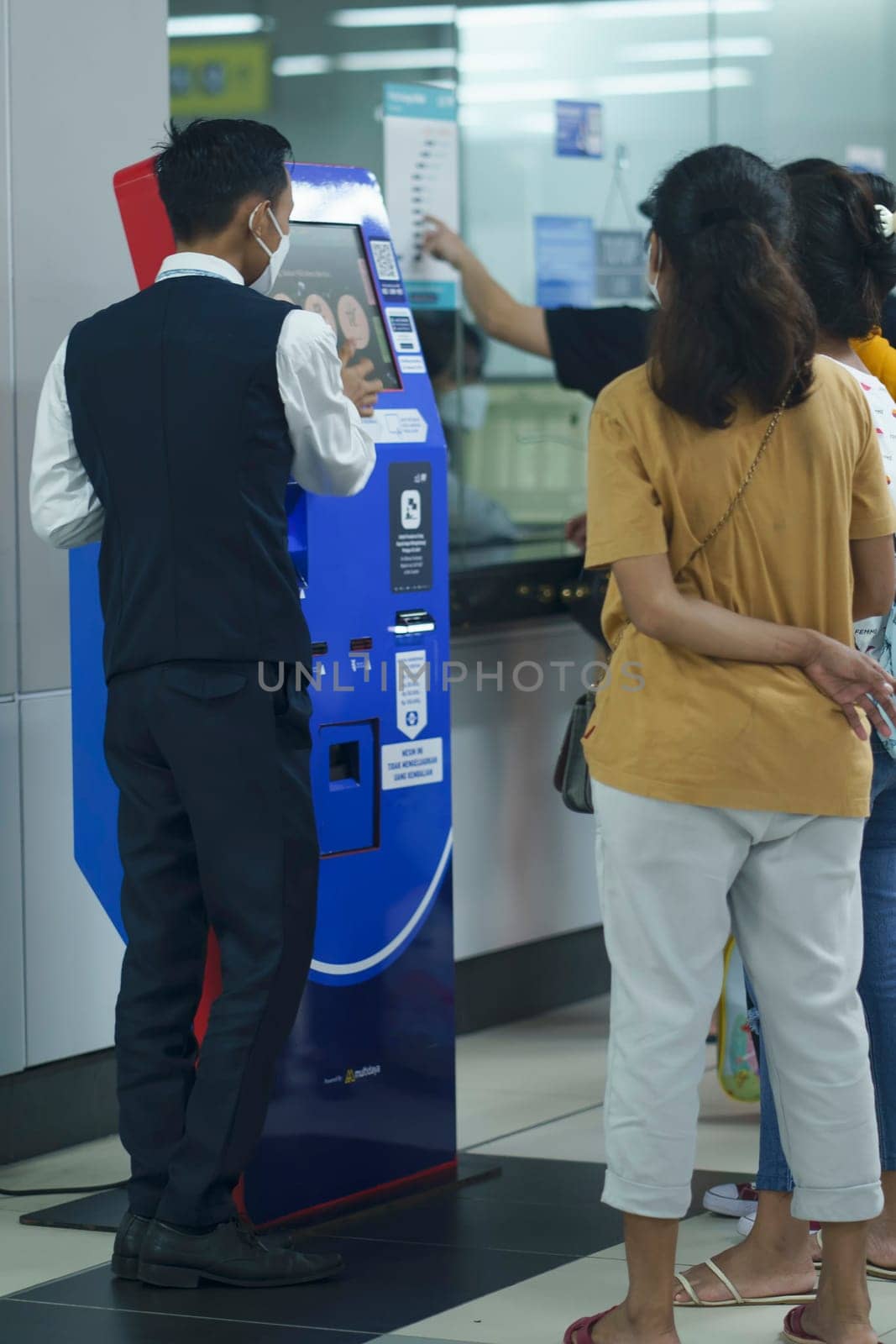 An officer is helping people at the ticket machine at the MRT Station, Jakarta, Indonesia. April 20, 2023. Publice service photography.