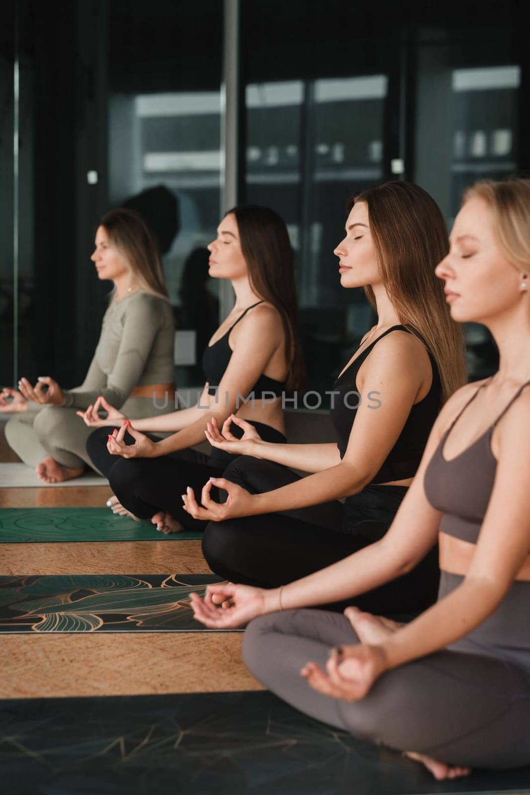 A group of beautiful girls are doing yoga in the fitness room. The concept of a healthy lifestyle by Lobachad