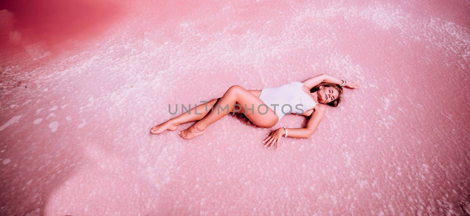 Woman in a pink salt lake banner . She lies in a white bathing suit. Wanderlust photo for memory.