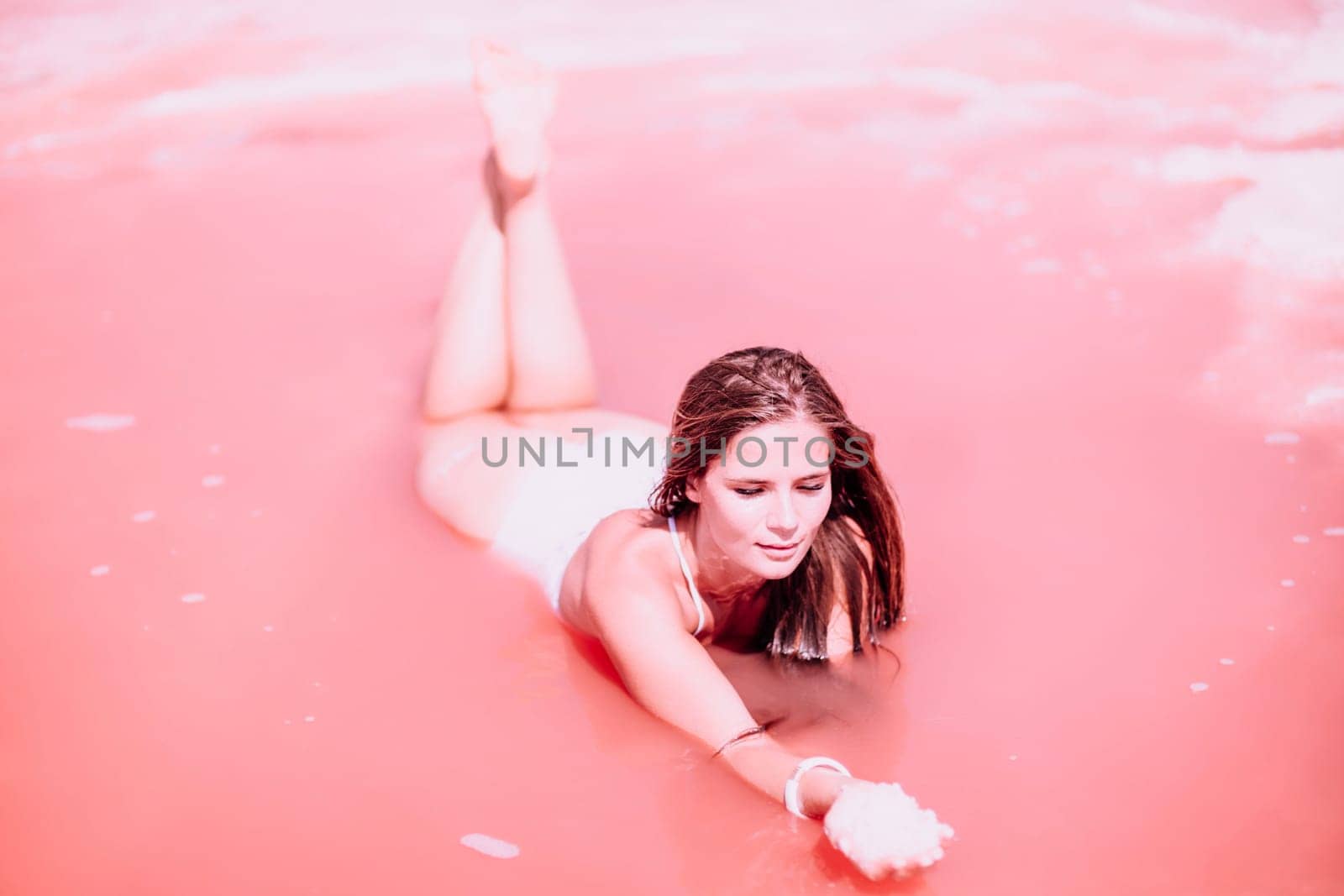 Woman in a pink salt lake. She lies in a white bathing suit. Wanderlust photo for memory by Matiunina