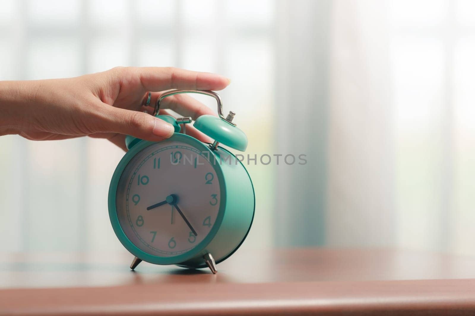 The bell alarm clock is turned off by hand in the morning for the concept of time management