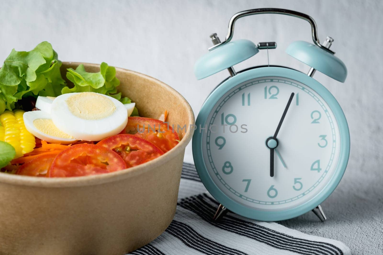 Fresh healthy salad with an alarm clock for the concept of food, time management, diet and heathy eating concept