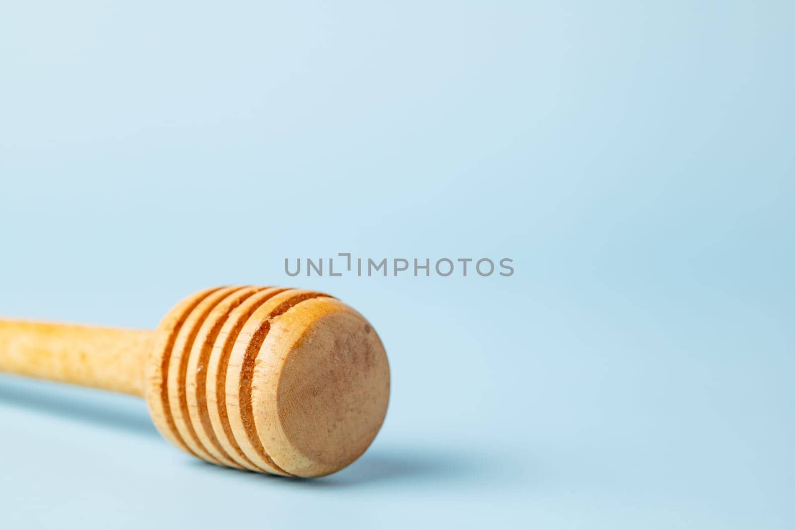 Closeup of a honey dipper on blue background for kitchen utensils concept.