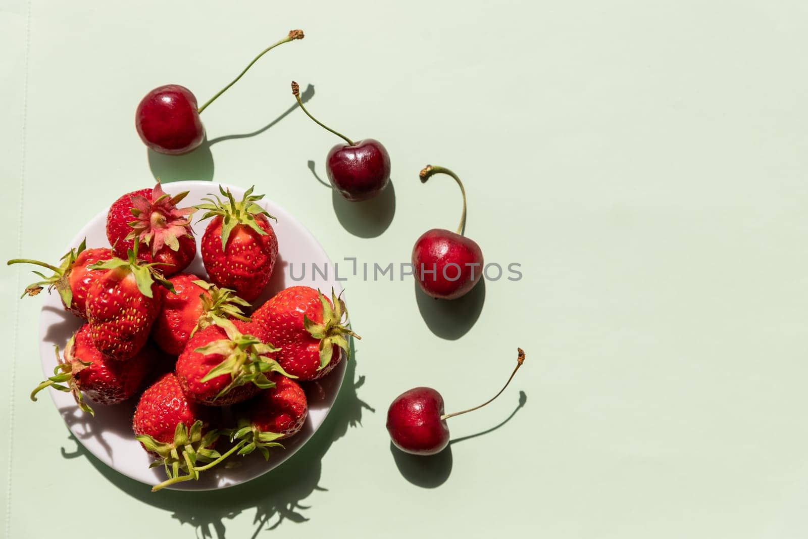 Heap of fresh strawberries in ceramic bowl on rustic white wooden background.