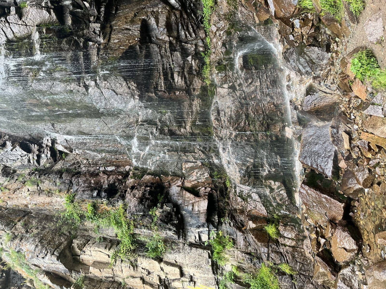 Waterfall on a stone cliff view on a summer day.