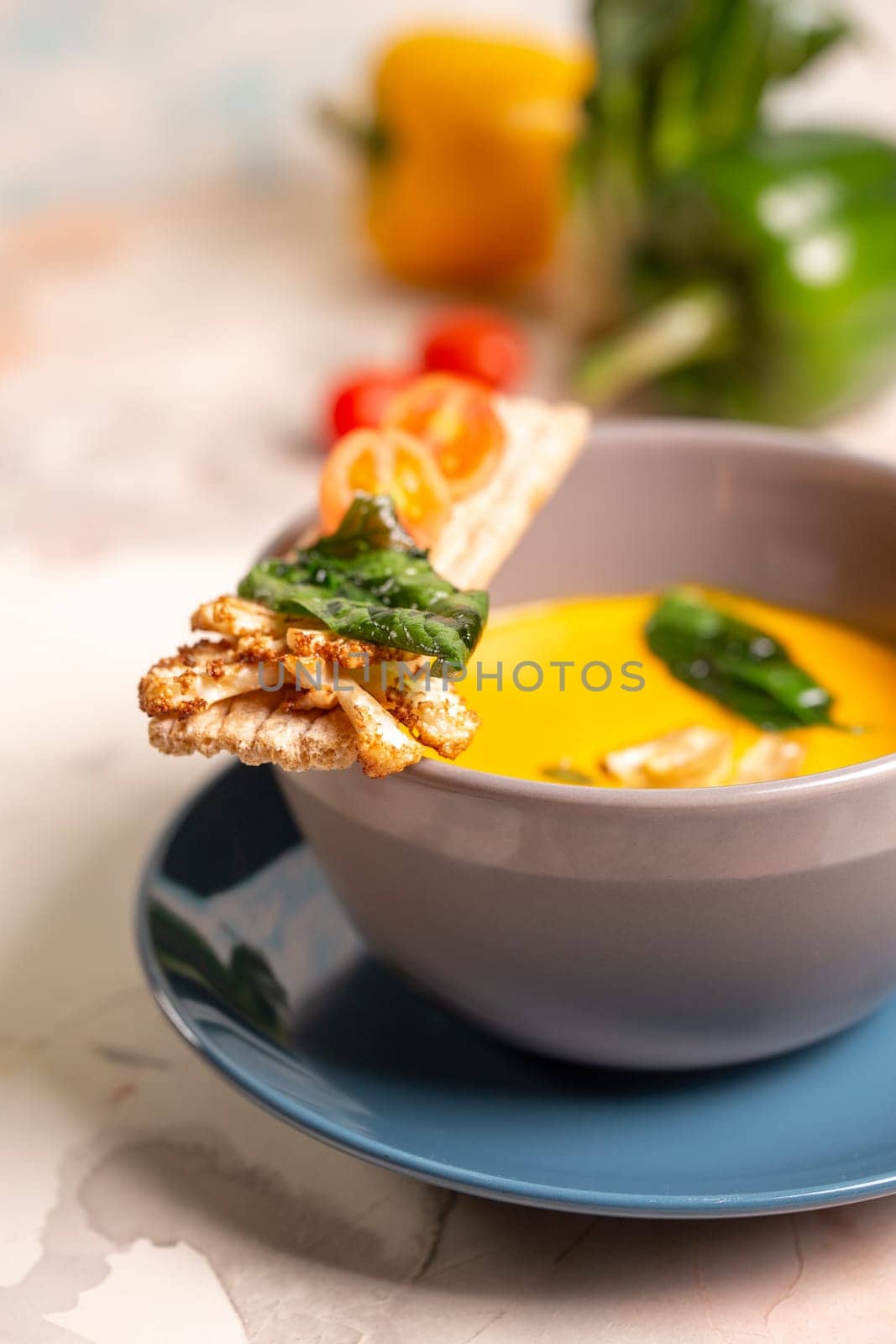 bright yellow pumpkin soup with seeds in a plate on the table by Pukhovskiy