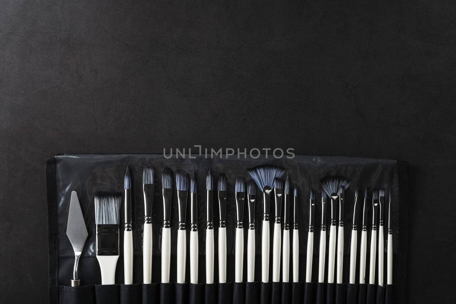 Art tools in a pencil case on a black background by AlexGrec