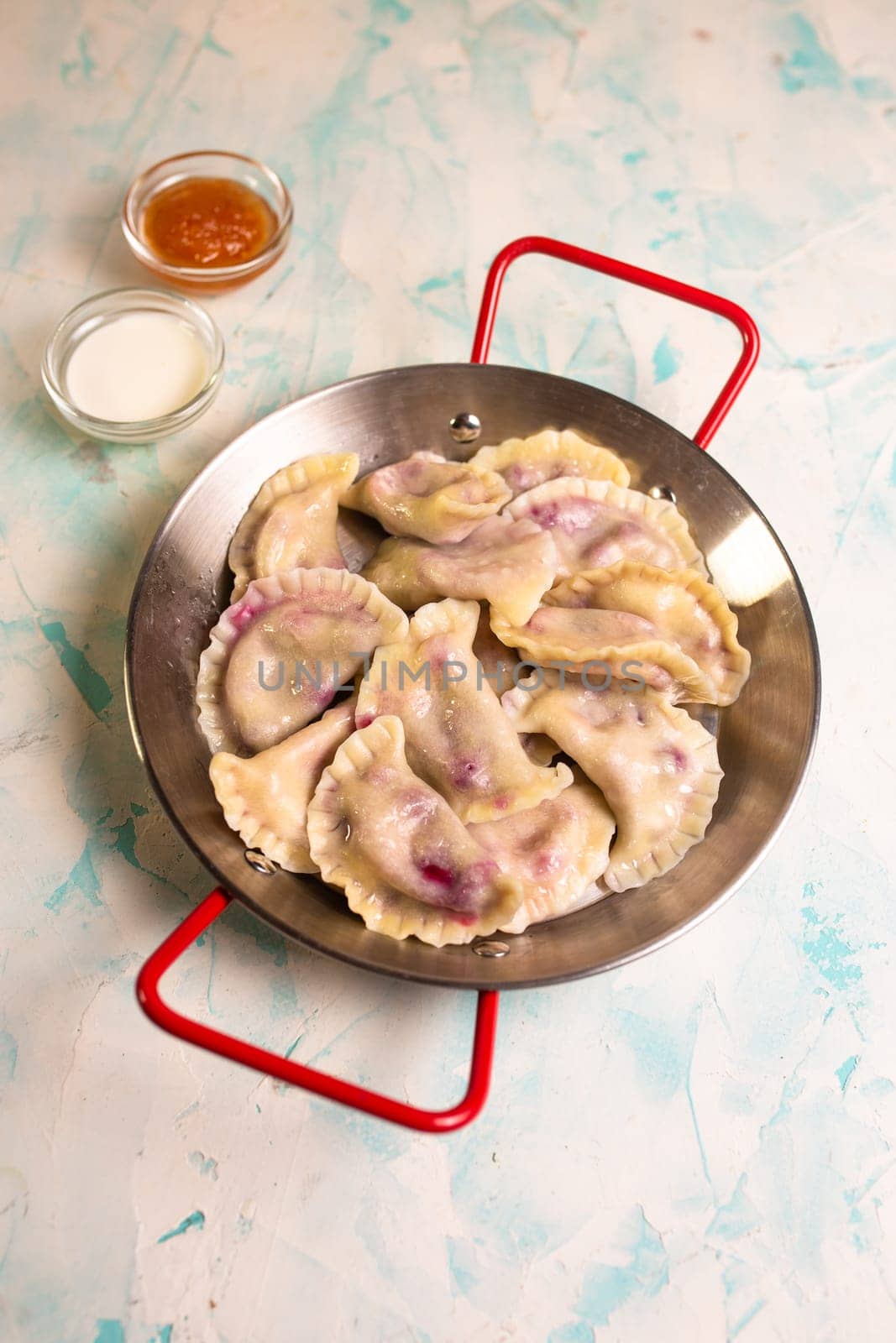 dumplings with berries and jam. a frying pan of dumplings on the background.