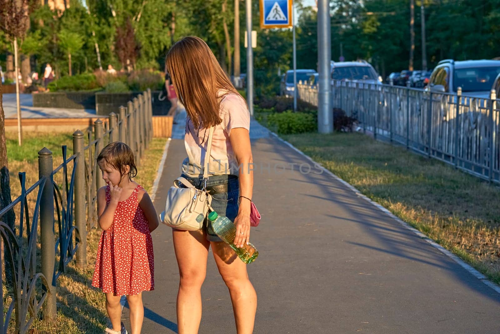 Cute mommy educates and scolds a wet child outdoors in a summer park by jovani68