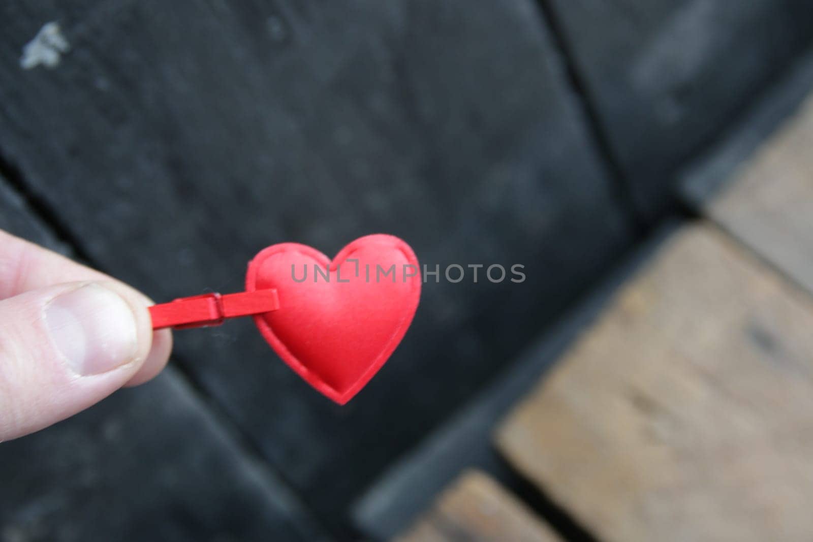 St. Valentine concept. A hand holds a red heart on a vintage background.