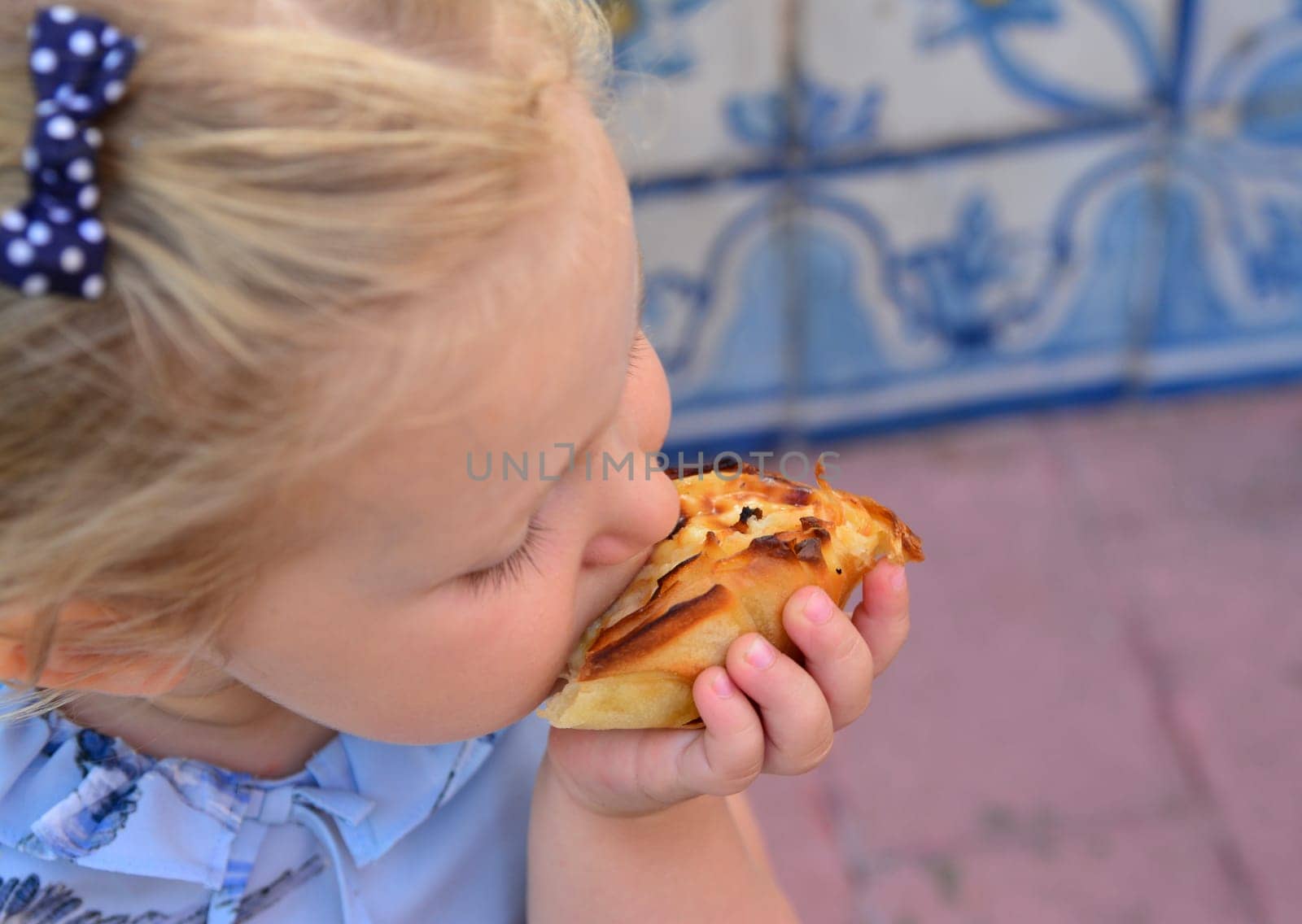 The girl is eating Pasteis de Belem egg tart. Azulejos tile on a background