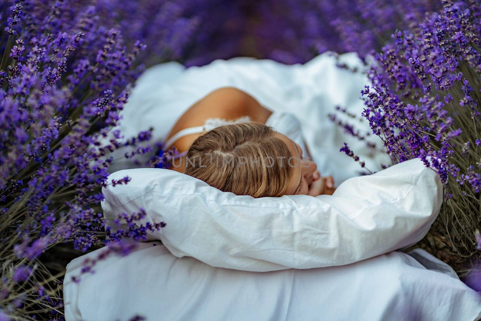 A middle-aged woman lies in a lavender field and enjoys aromatherapy. Aromatherapy concept, lavender oil, photo session in lavender.