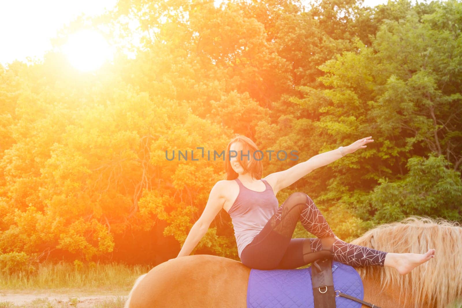 young woman doing yoga on a horse against the backdrop of trees by glavbooh