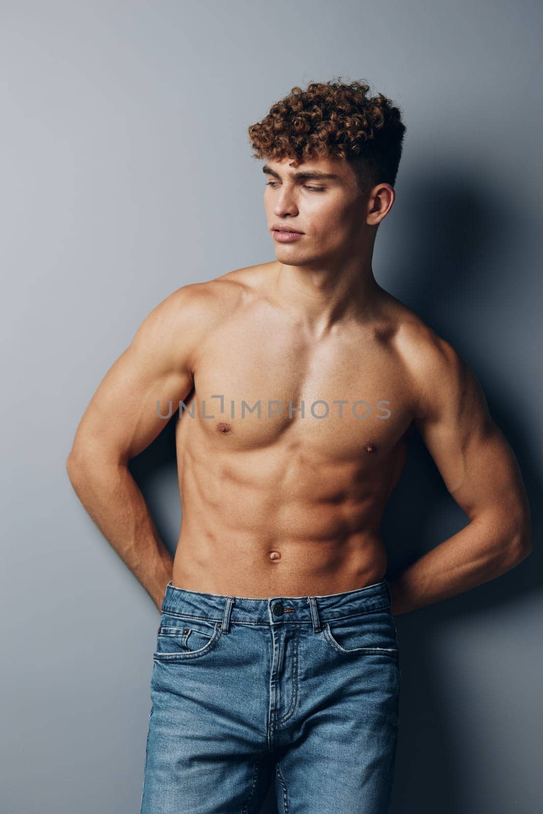 man healthy muscle young naked lifestyle smile bicep guy jeans athletic gray background standing shirtless torso bodybuilder