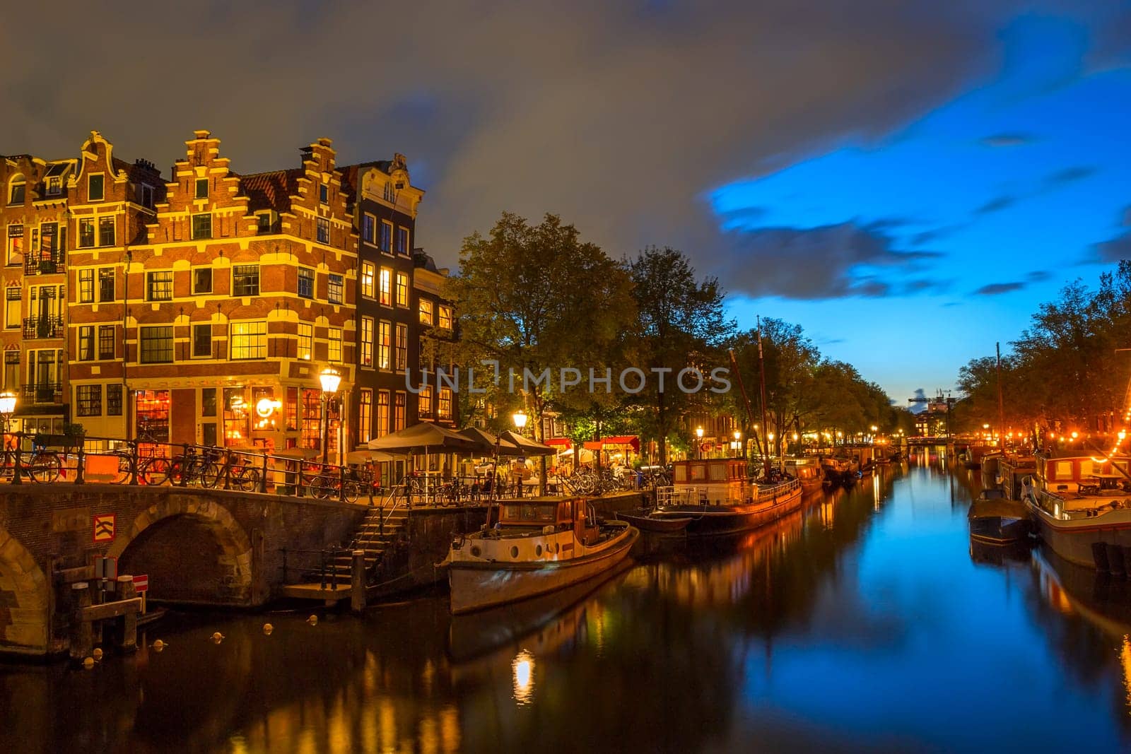 Netherlands. Evening embankment of Amsterdam. Stone bridge, bicycles near the fence and houseboats