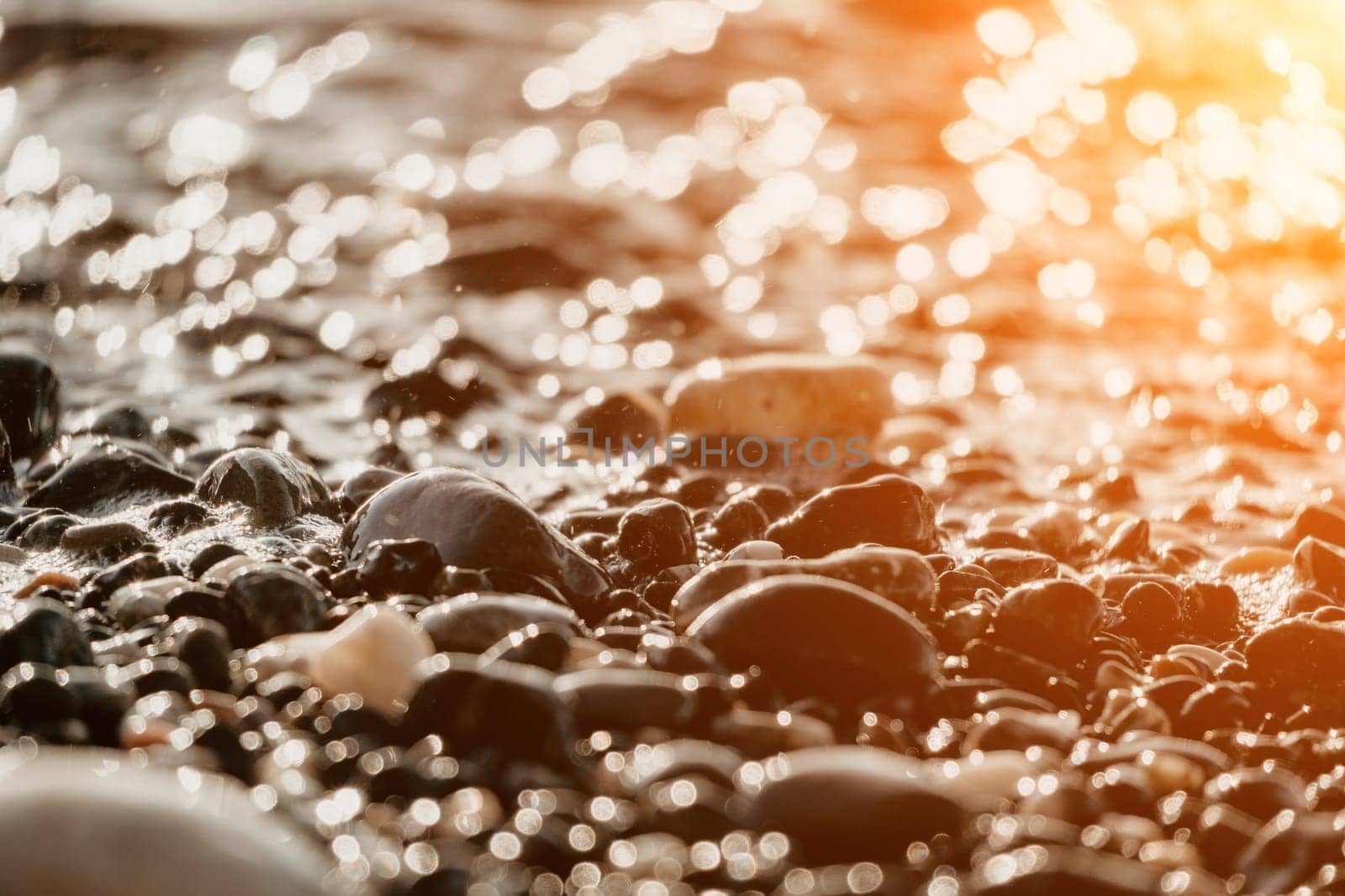 Blurred golden sea at sunset. The sun reflects and sparkles on the waves with bokeh, illuminating the golden sea. Holiday recreation concept. Abstract nautical summer ocean sunset nature background. by panophotograph