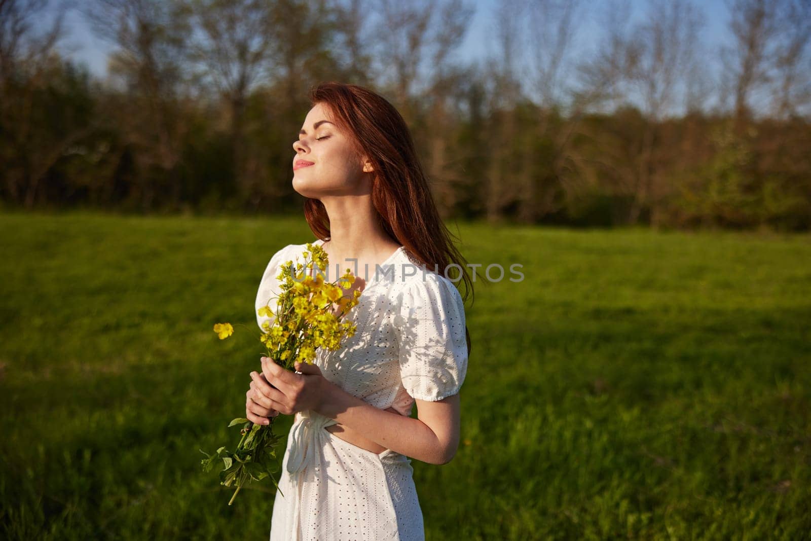 portrait of a beautiful woman with a bouquet of buttercups in her hands in a white dress in nature by Vichizh