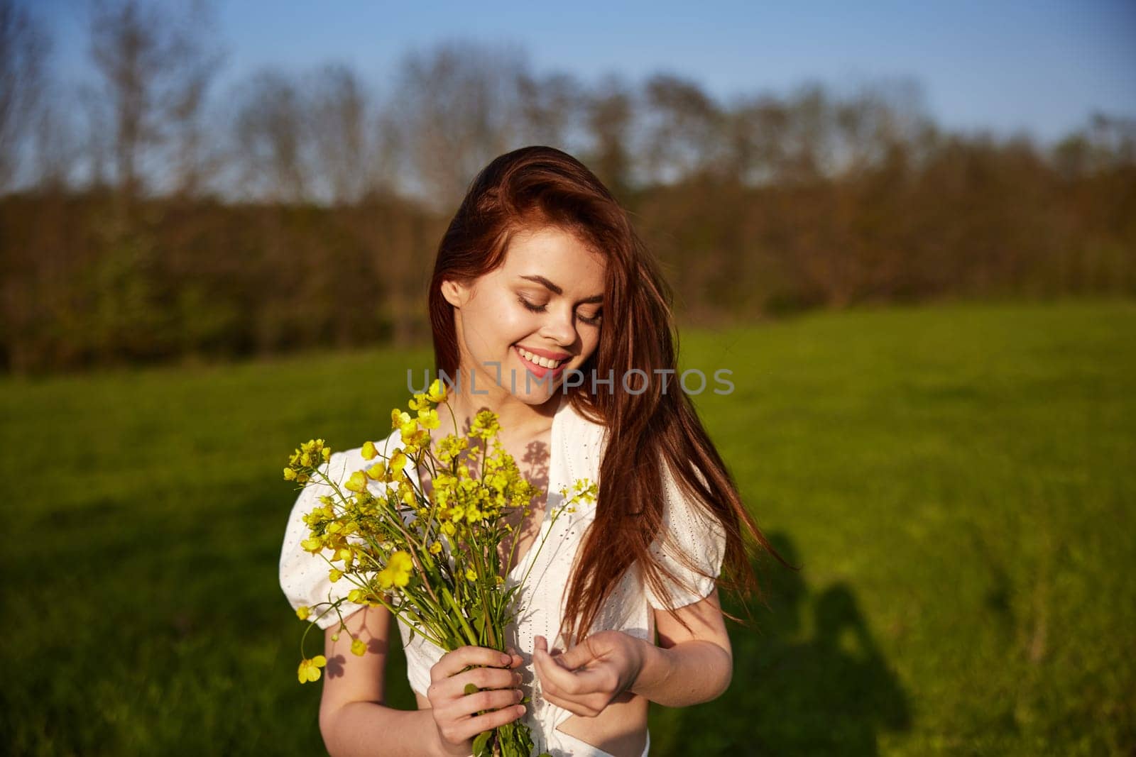 portrait of a happy woman with a bouquet of buttercups walking in the field by Vichizh