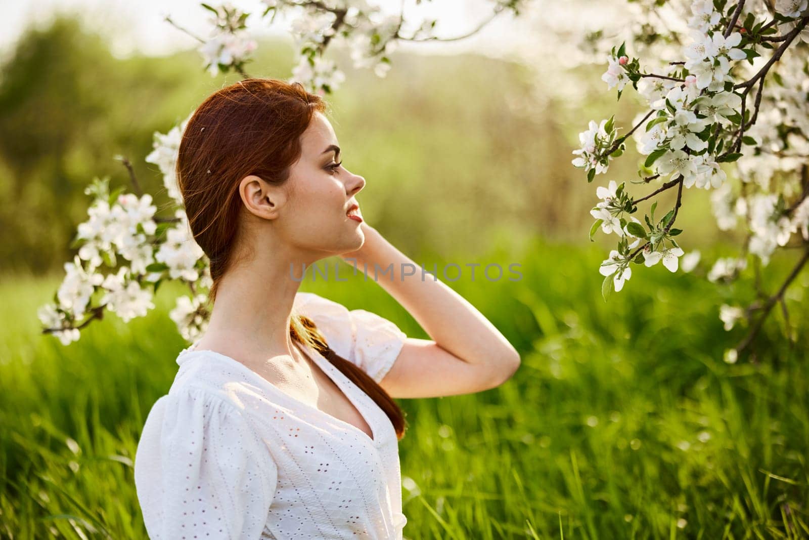 portrait of a beautiful woman looking at the flowers of an apple tree by Vichizh