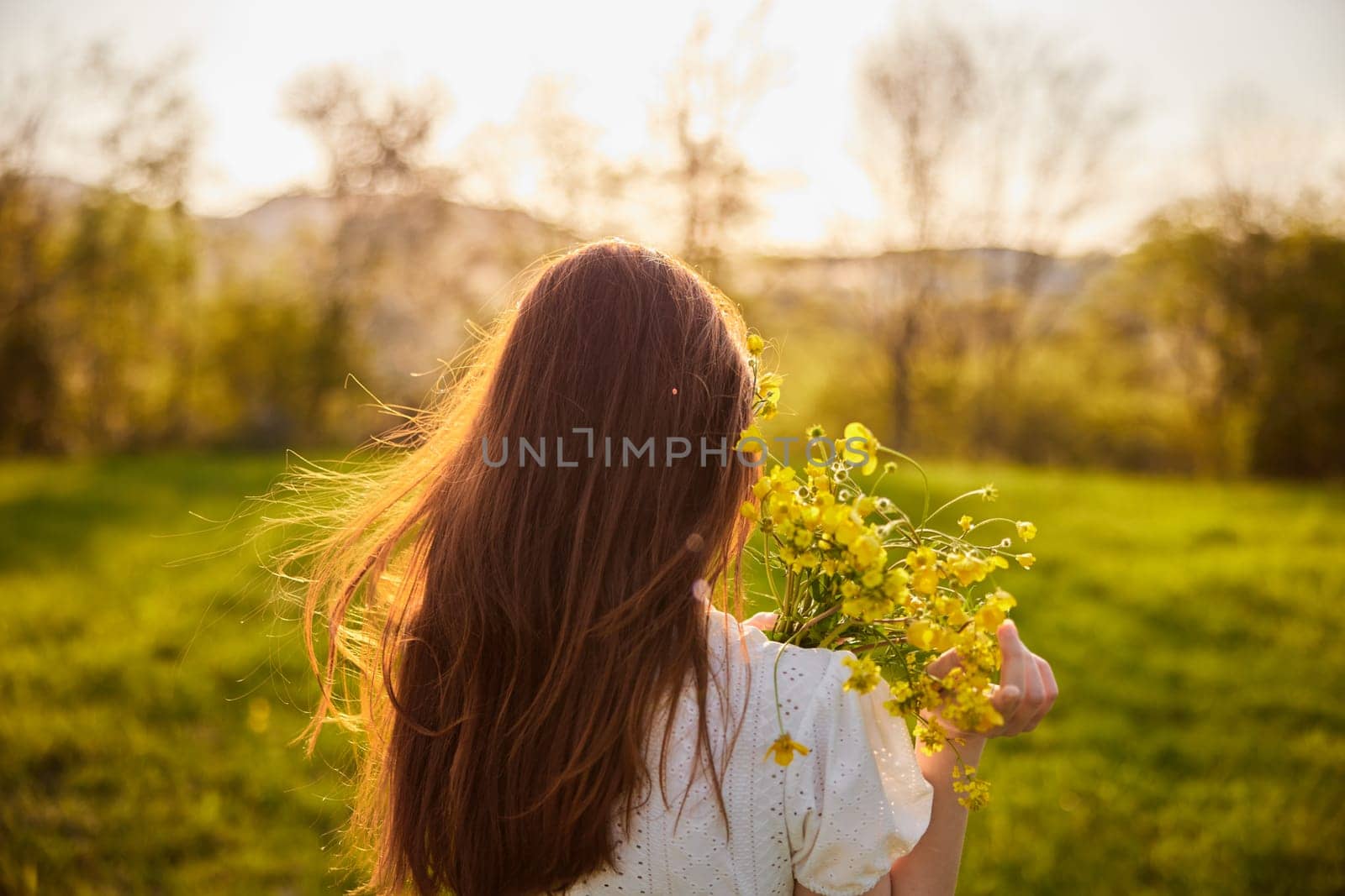 photo from the back of a red-haired woman with a bouquet of flowers in the rays of the setting sun by Vichizh