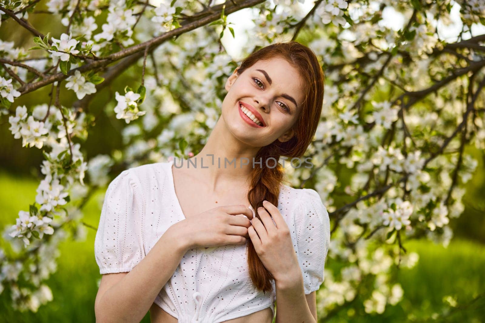 joyful woman posing standing next to a flowering tree enjoying nature by Vichizh