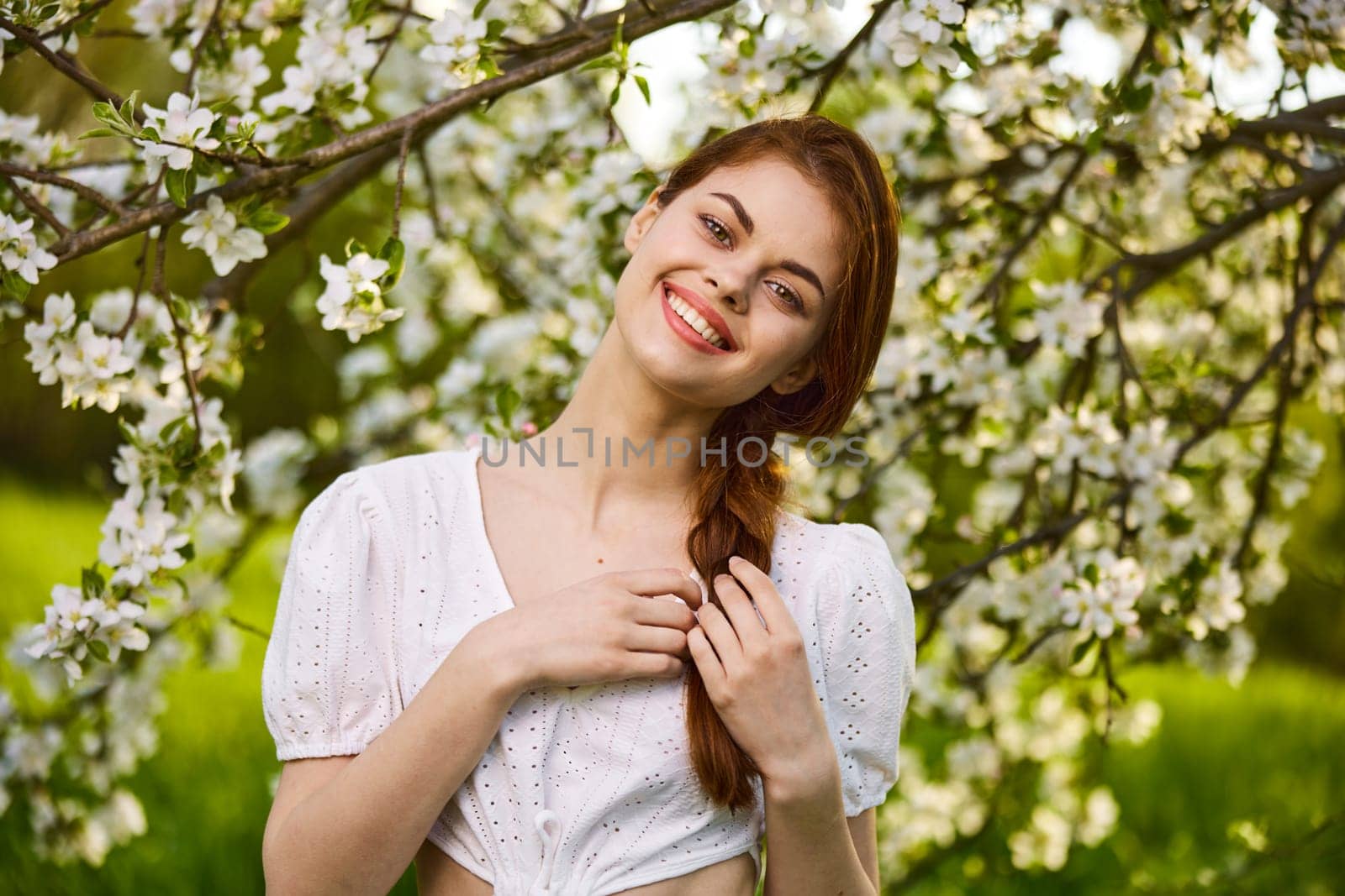 joyful woman posing standing next to a flowering tree enjoying nature. High quality photo