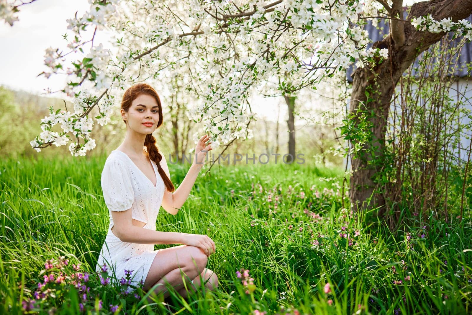 Young beautiful woman in a white dress posing in garden by Vichizh