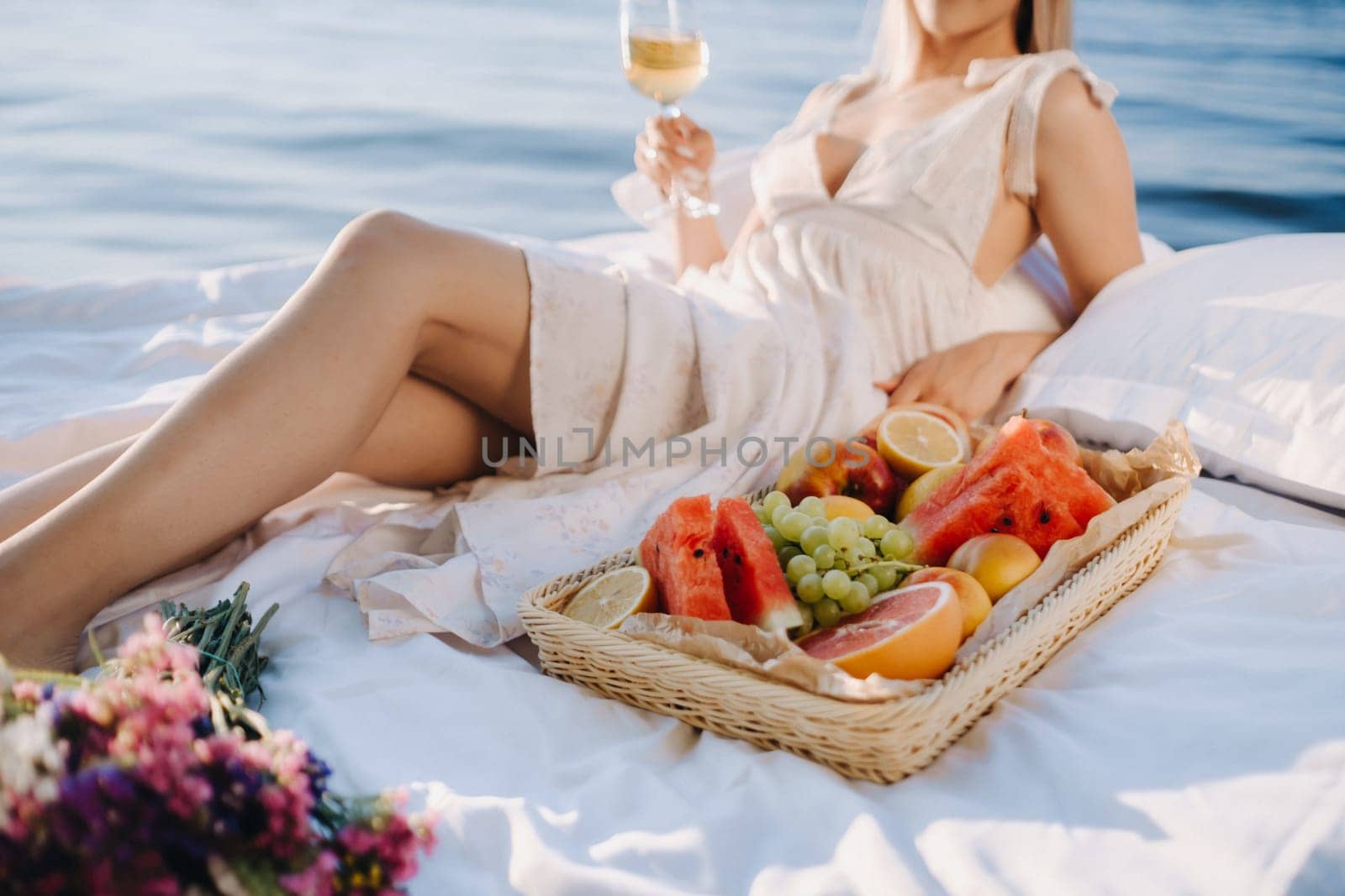 a woman in bed is resting on the seashore with a glass of champagne and fruit.