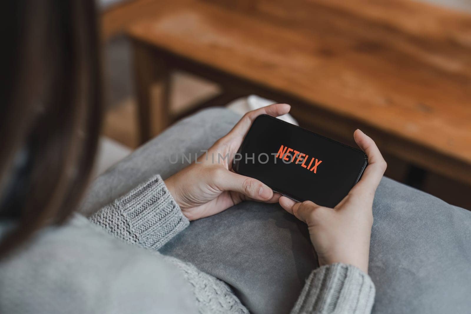 CHIANG MAI, THAILAND, APR 17, 2022: Woman hand holding Smart Phone with Netflix logo on Apple iPhone 14. Netflix is a global provider of streaming movies and TV series...