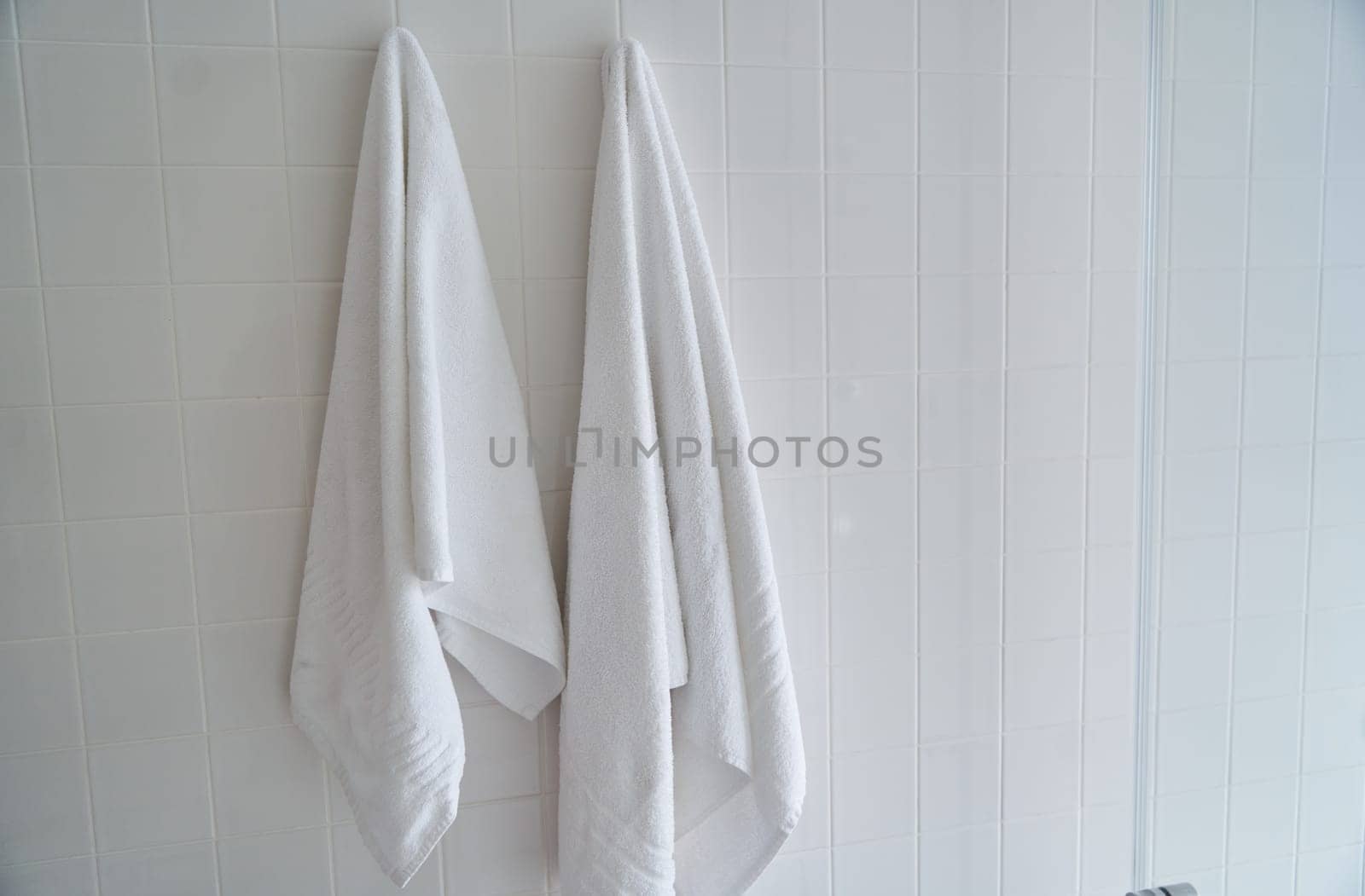 Two white towels hanging in the hotel shower room. High quality photo