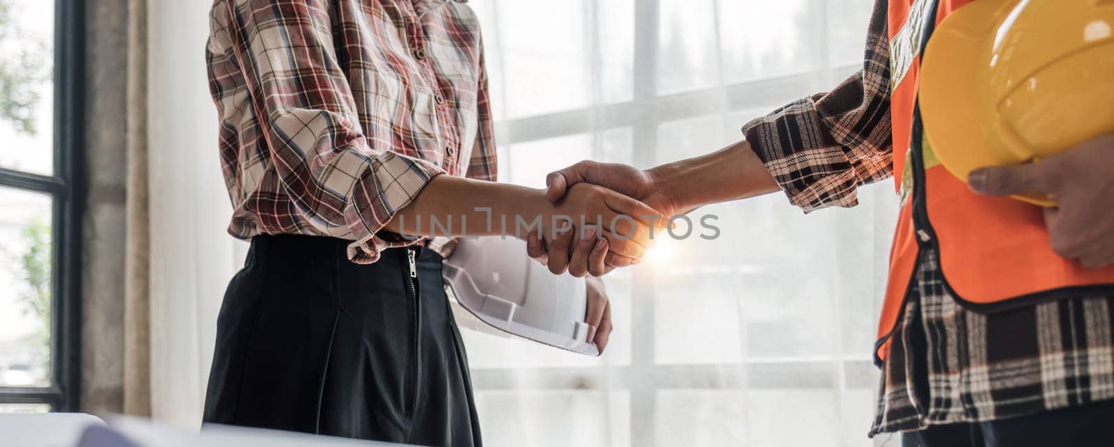 Architect and engineer construction workers shaking hands while working for teamwork and cooperation concept after finish an agreement in the office construction site, success collaboration concept..