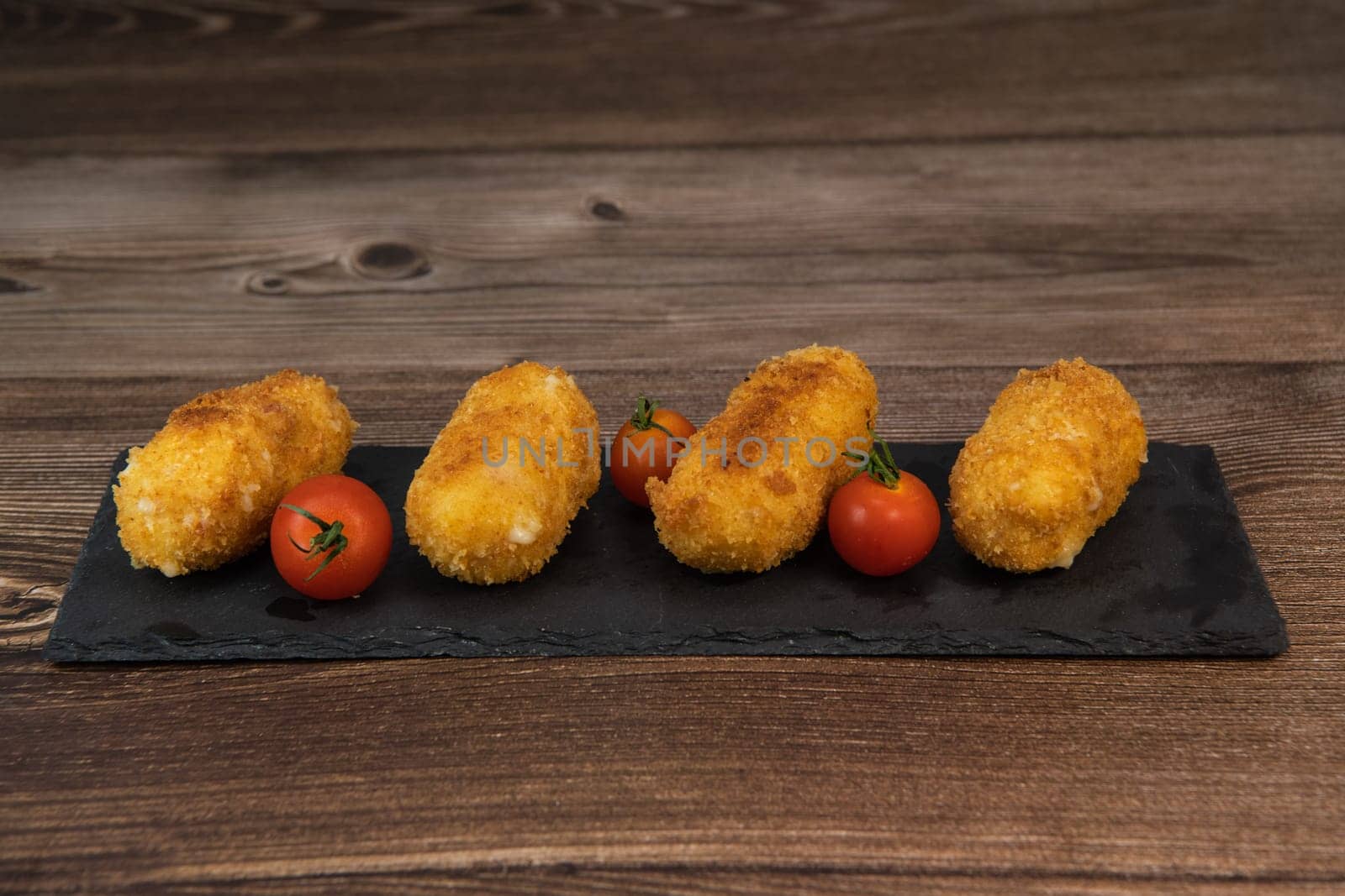 Homemade traditional Spanish croquettes or croquetas on a black plate with fork, Tapas food, High quality photo