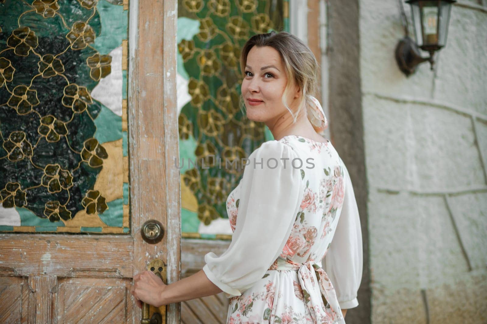 a woman in a flower dress opens the door to the house.