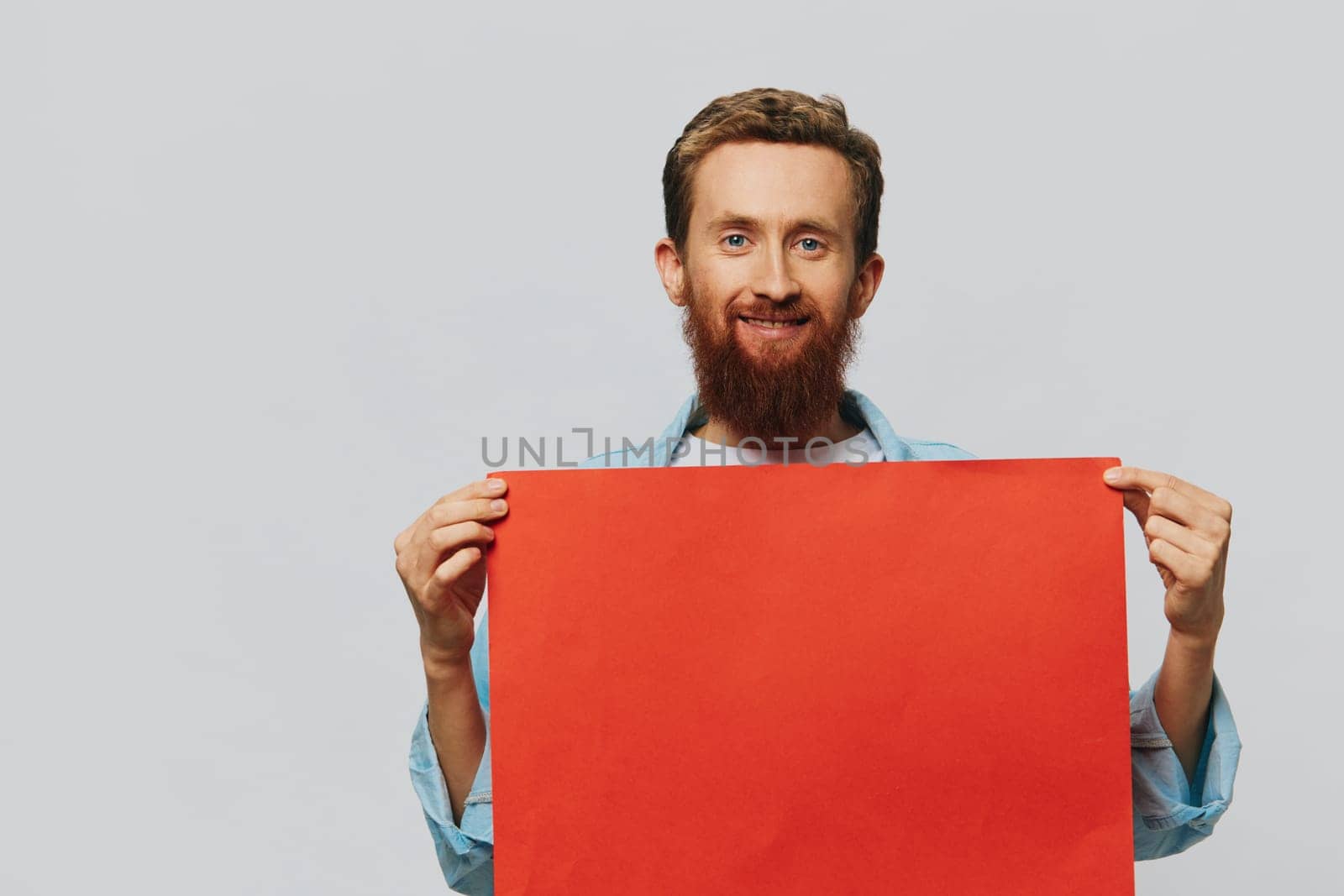 Portrait of an adult male on a gray background with a red piece of paper for your design and text, layout, copy space, space for text. High quality photo