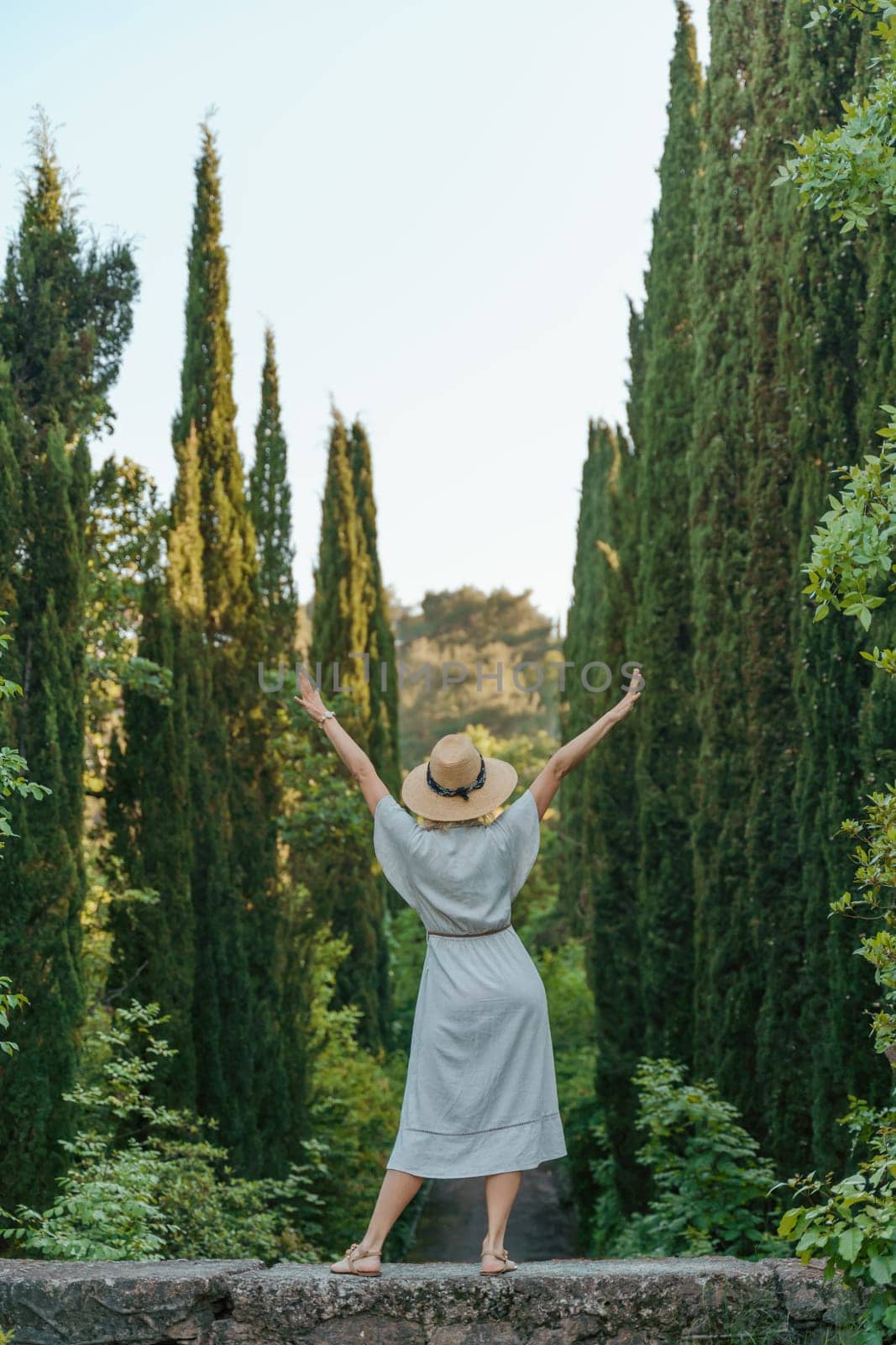 happy woman wearing a fedora hat while standing in the woods by Matiunina