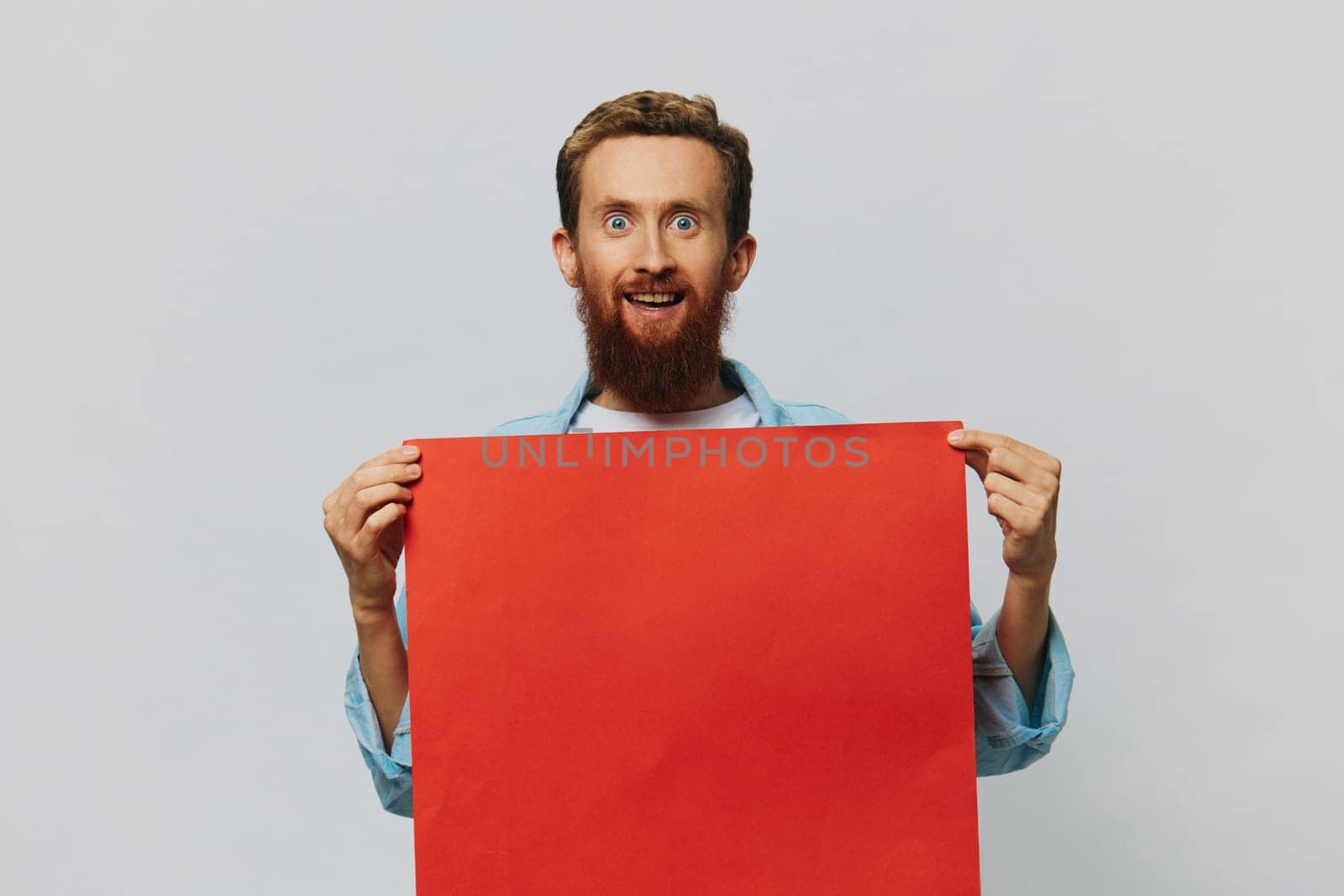 Portrait of an adult male on a gray background with a red piece of paper for your design and text, layout, copy space, space for text by SHOTPRIME